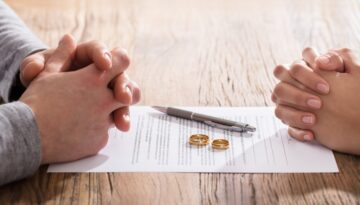 Couple sitting around divorce papers with their wedding rings in the center. Bosshard Parke Wisconsin Divorce.