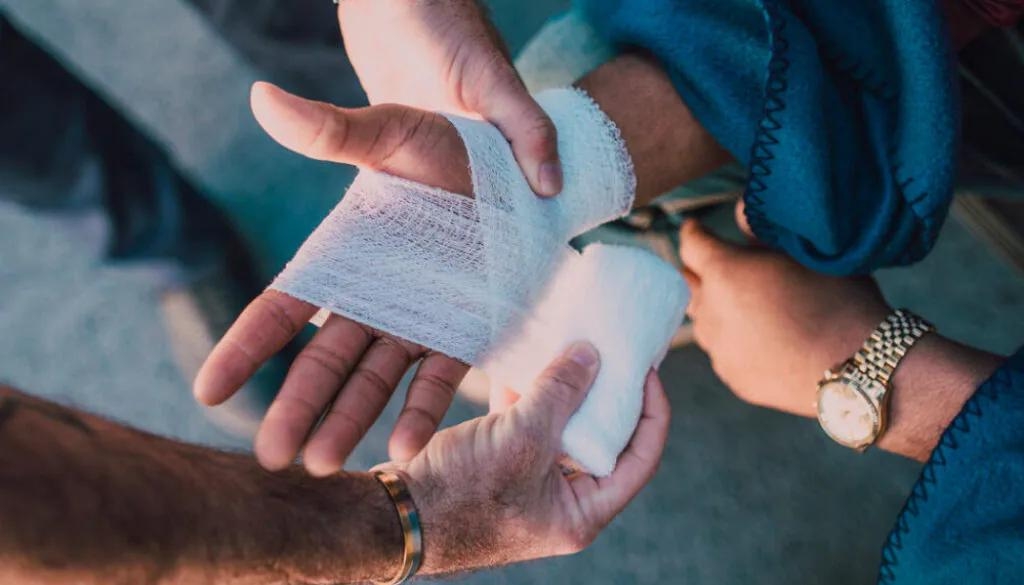 Paramedic bandaging an injured person's hand. Bosshard Parke Personal Injury Attorney.