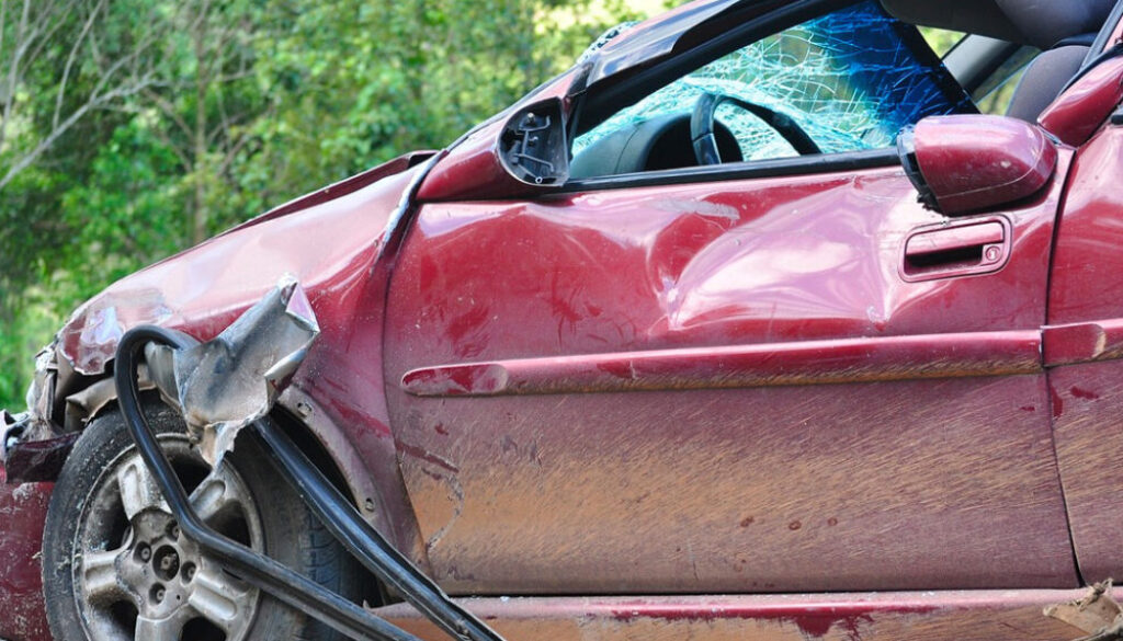 Red car with damage to the front quarter panel after a car accident.