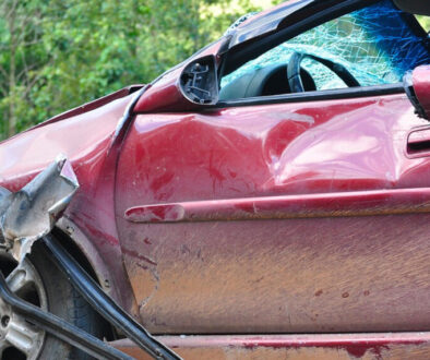 Red car with damage to the front quarter panel after a car accident.