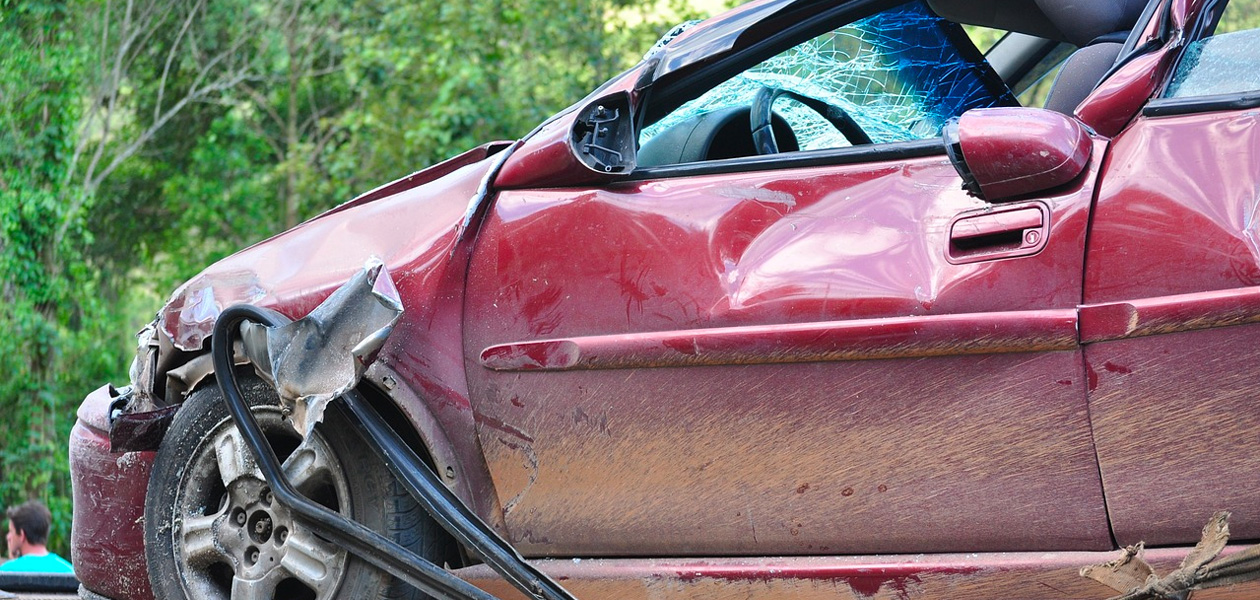 Red car with damage to the front quarter panel after a car accident.