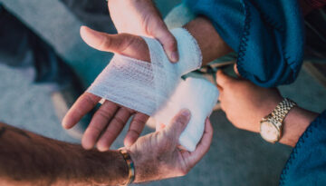 Paramedic bandaging an injured person's hand.
