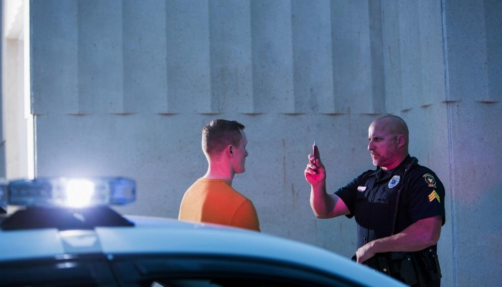 Police officer uses a pen to perform a field sobriety test on a man.