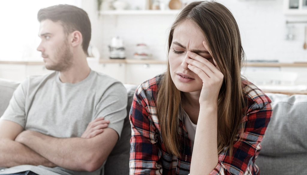 Man crossing his arms while woman looks stressed.