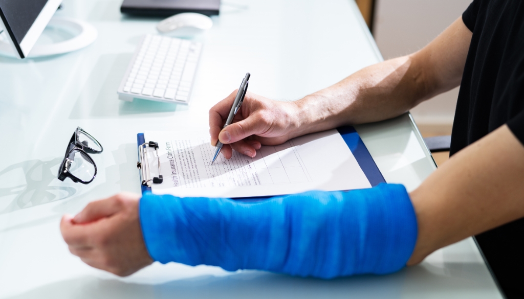 Person with a broken arm filling out a worker's compensation health insurance claim form.