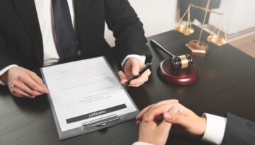 Two business people sitting at a desk with a contract in front of them.