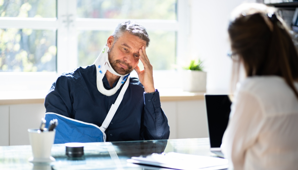 Man wearing a neck brace and arm sling meets with a workers' compensation attorney in Wisconsin.