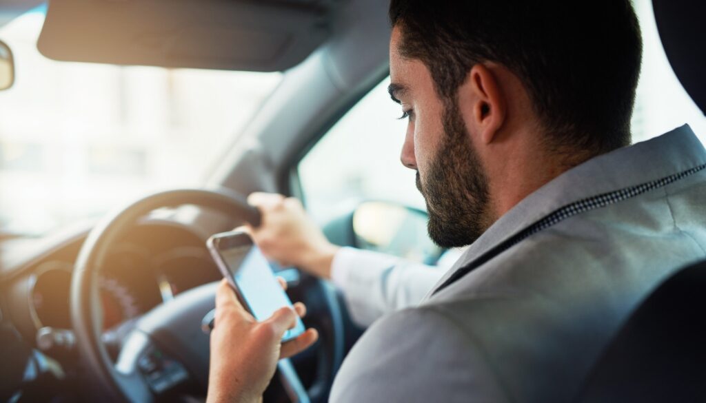 A man operating a vehicle while looking at his phone.