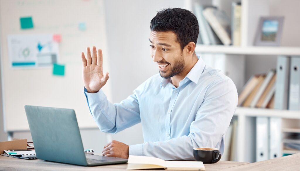 A man waving at the camera while in a virtual meeting to notarize a will.