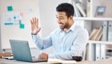 A man waving at the camera while in a virtual meeting to notarize a will.