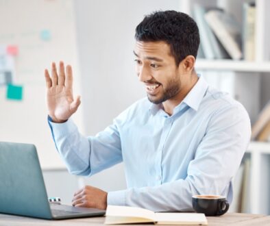 A man waving at the camera while in a virtual meeting to notarize a will.