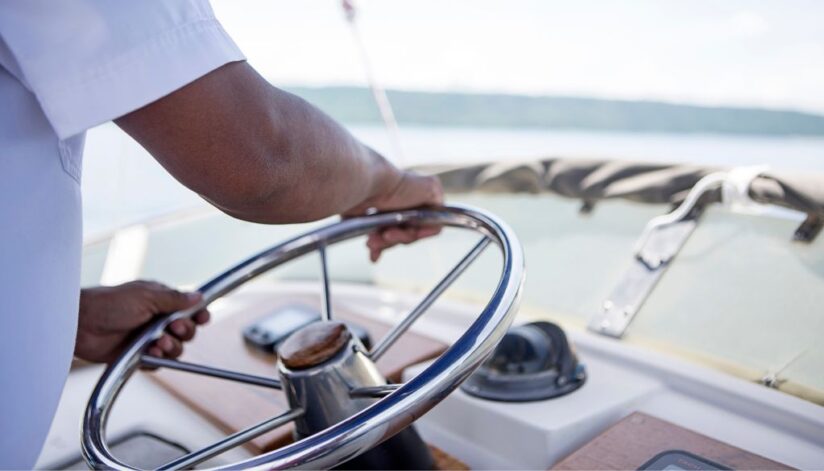 A close up of a man driving a boat along the Mississippi River.