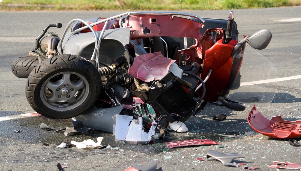 A crushed motorcycle in the road after an accident.