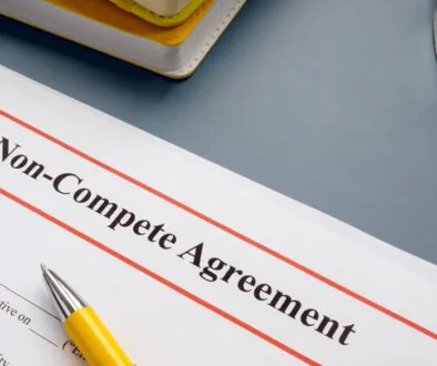 A non-compete agreement laid out on a table with a pen and glasses.