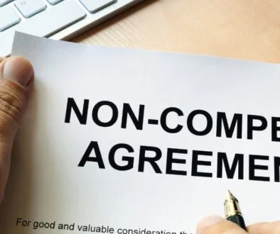 A person holding a pen and non-compete agreement.