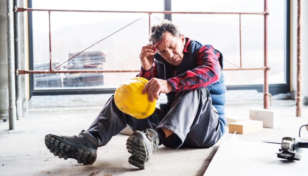 A man on the floor of a construction site with a head injury.