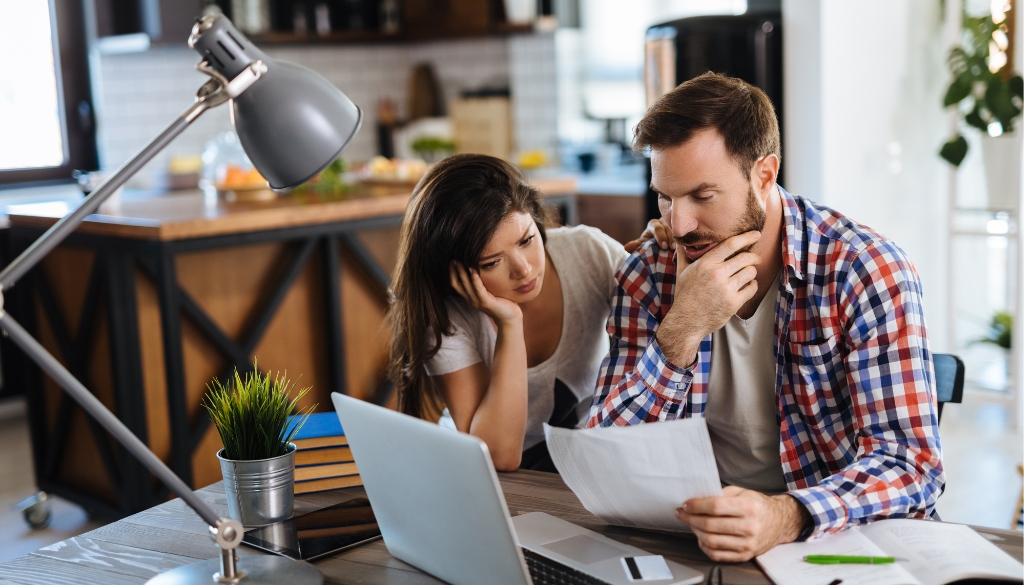 A couple reviewing medical and insurance bills at home, looking concerned as they go through a Wisconsin personal injury case.