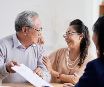 An elderly couple smiling while discussing estate planning documents with an attorney.