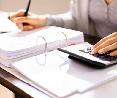 Close-up of a business professional reviewing financial documents with a calculator, preparing for an IRS audit in a well-organized workspace.