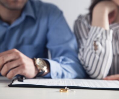 A couple reviewing divorce paperwork at a table with a wedding ring placed on the document.