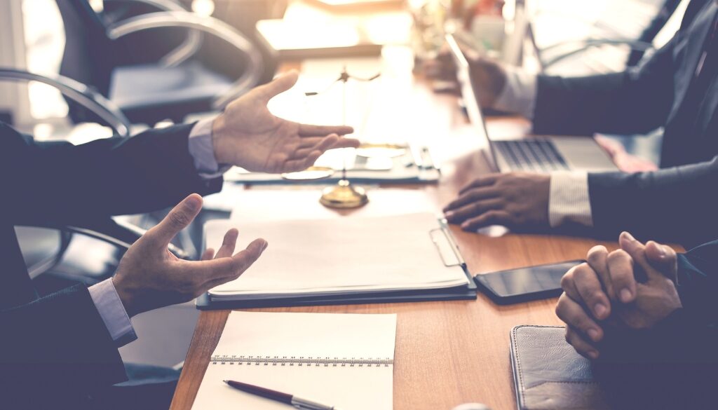 Professionals having a meeting in a law office, with documents, a laptop, and a gavel on the table.