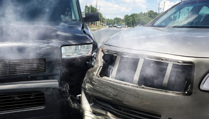 Two vehicles with front-end damage after a car accident on a Wisconsin roadway, with smoke rising from both hoods.