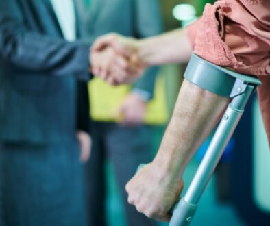 Close up of an injured worker using crutches shaking hands with a professional.