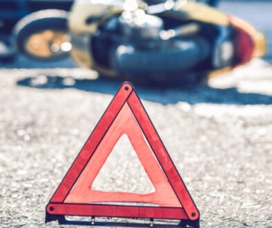 Warning triangle placed on the road near a crashed motorcycle, signaling a recent accident and potential injury at the scene.