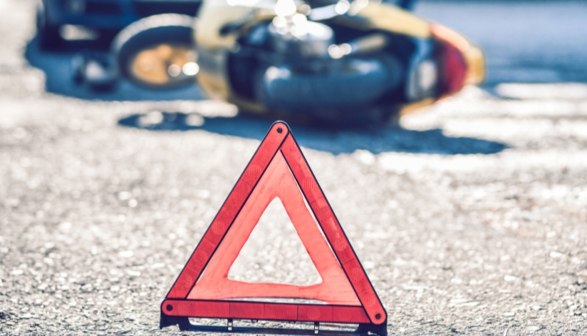 What To Do After A Motorcycle Accident In Wisconsin Warning triangle placed on the road near a crashed motorcycle, signaling a recent accident and potential injury at the scene.