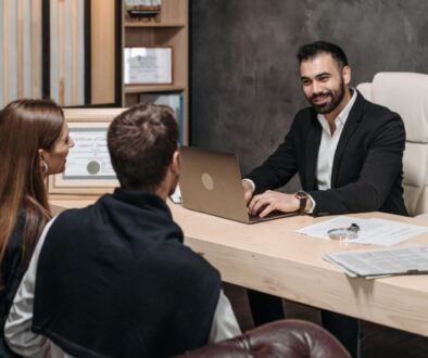 A newly engaged couple sitting across from a professional attorney in an office, and discussing a prenuptial agreement.
