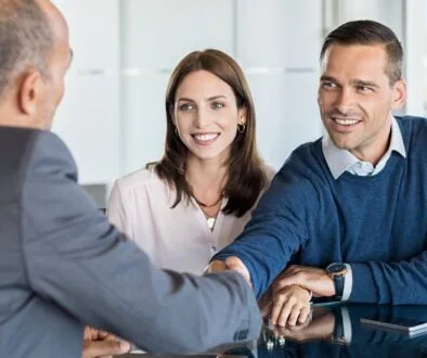 A smiling couple meets with an attorney during an initial consultation, shaking hands across a desk.