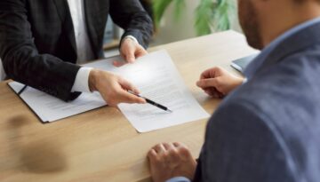 An attorney reviews and explains a settlement offer document to a client during a professional consultation in an office setting.