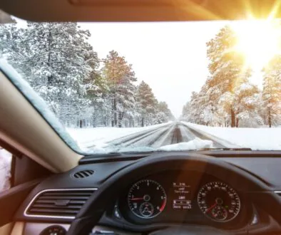 The view of the inside of a car driving down a snowy road surrounded by pine trees in Wisconsin.