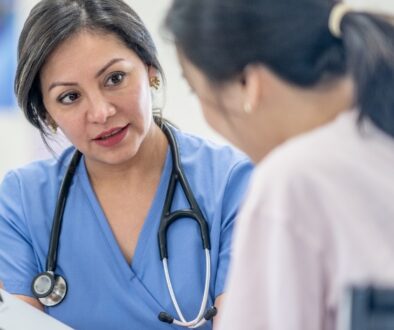 A doctor points at a chart while talking with a patient.