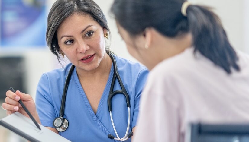 A doctor points at a chart while talking with a patient.