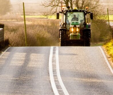 Tractor traveling on a rural Wisconsin road during autumn, highlighting farm equipment and roadway safety.