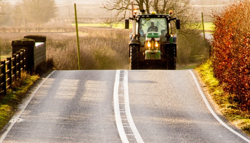 Tractor traveling on a rural Wisconsin road during autumn, highlighting farm equipment and roadway safety.
